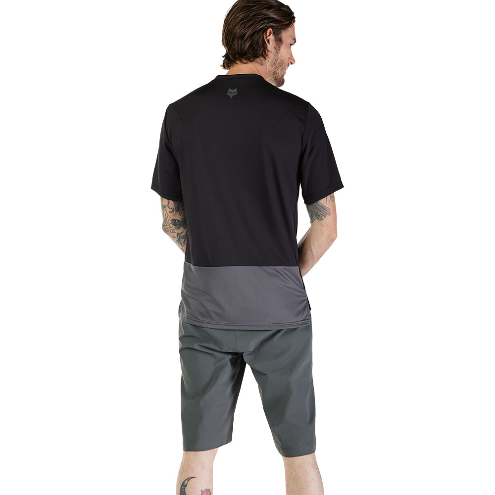 Man wearing a black t-shirt and gray shorts on a white background