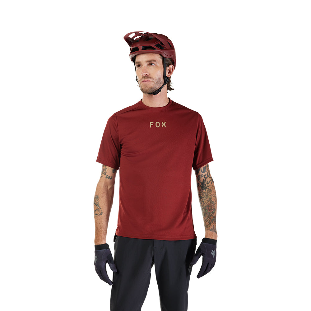 Man wearing a red 'Fox' t-shirt, black pants, and helmet on a white background