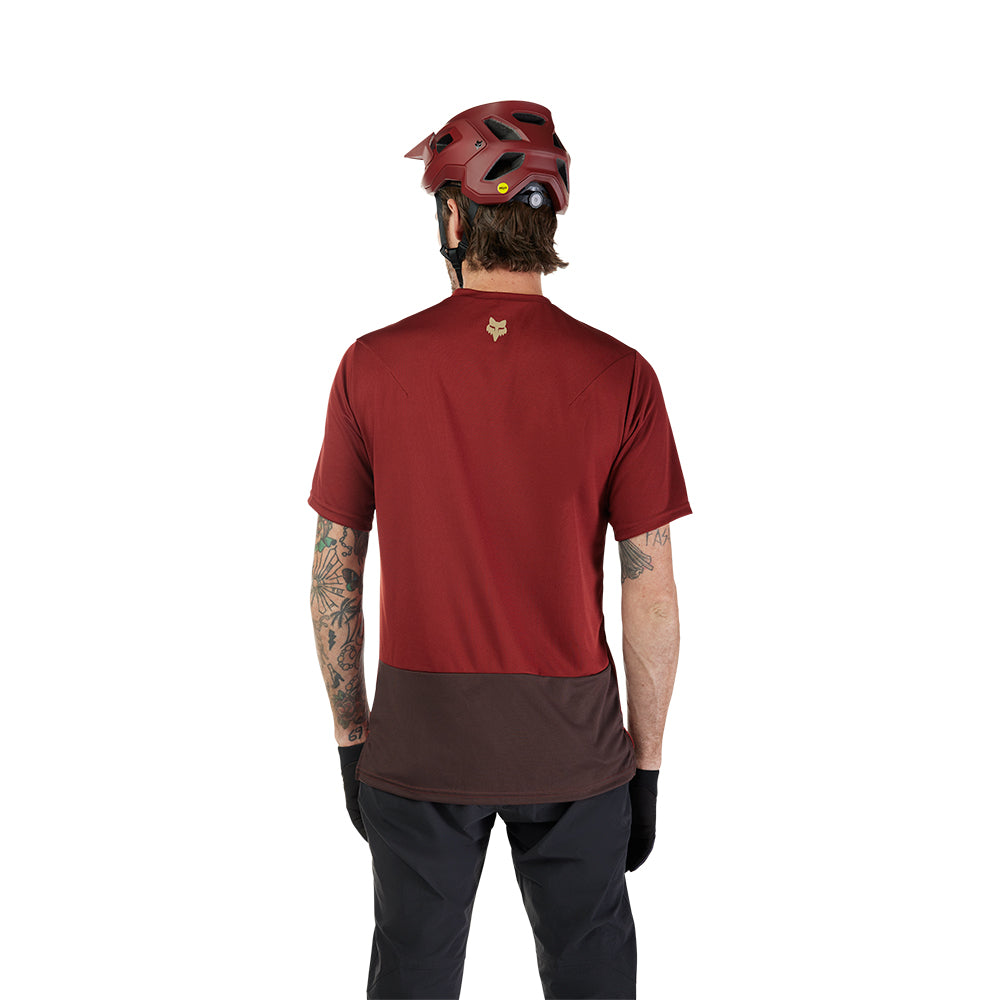 Person wearing a maroon athletic shirt and helmet on a white background
