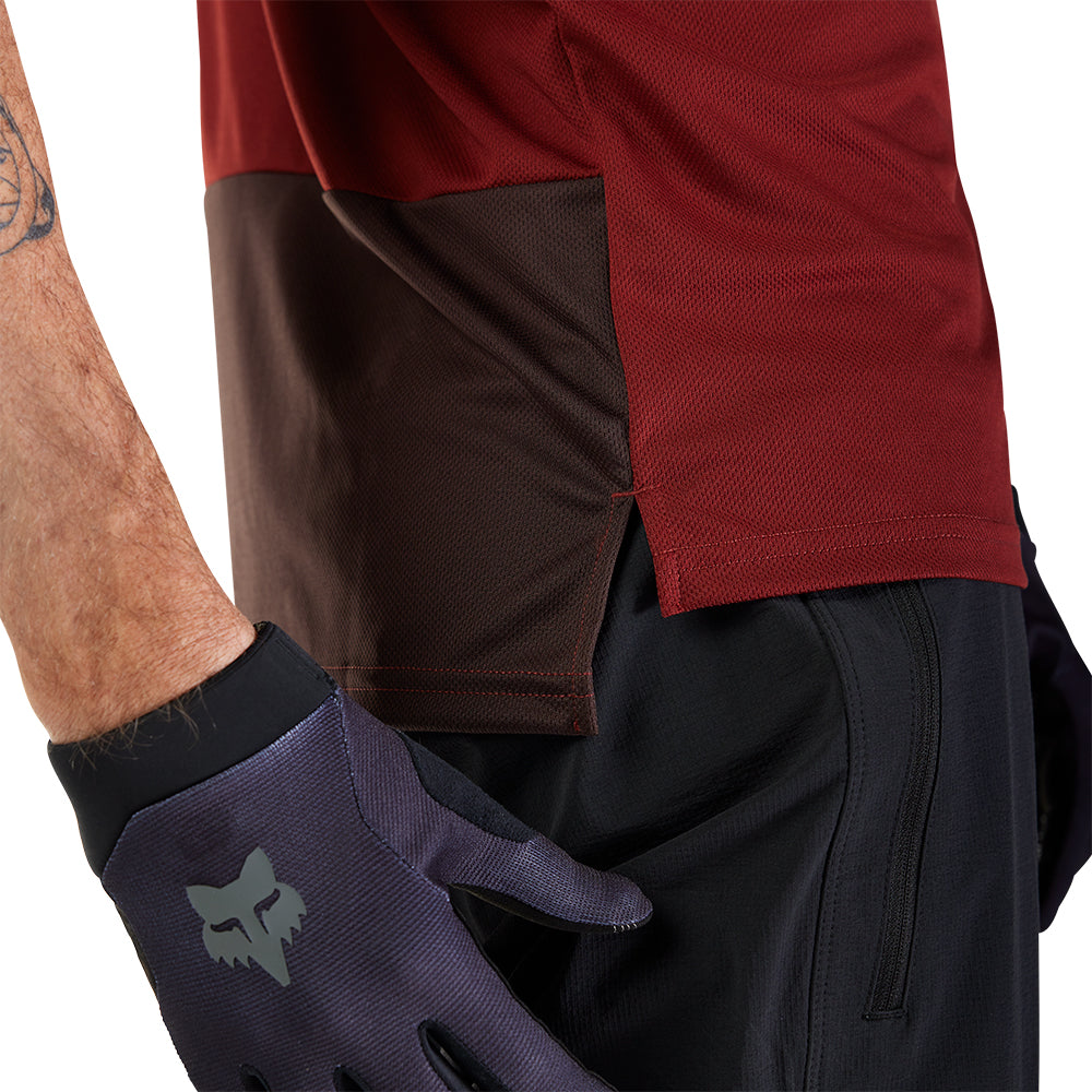 Person wearing a red and brown shirt with black gloves on a white background