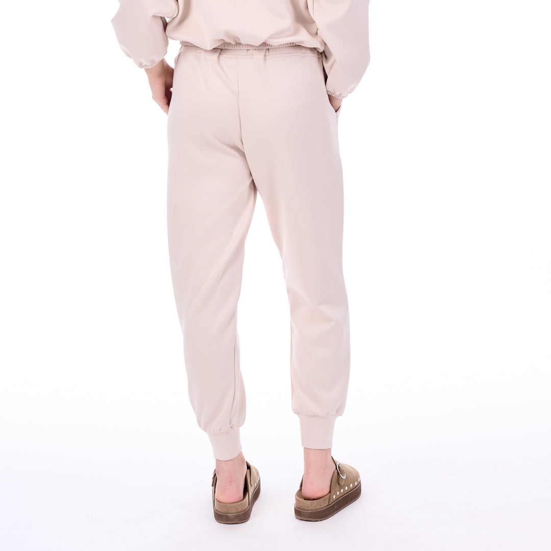 Person wearing a light pink outfit with matching pants on a white background