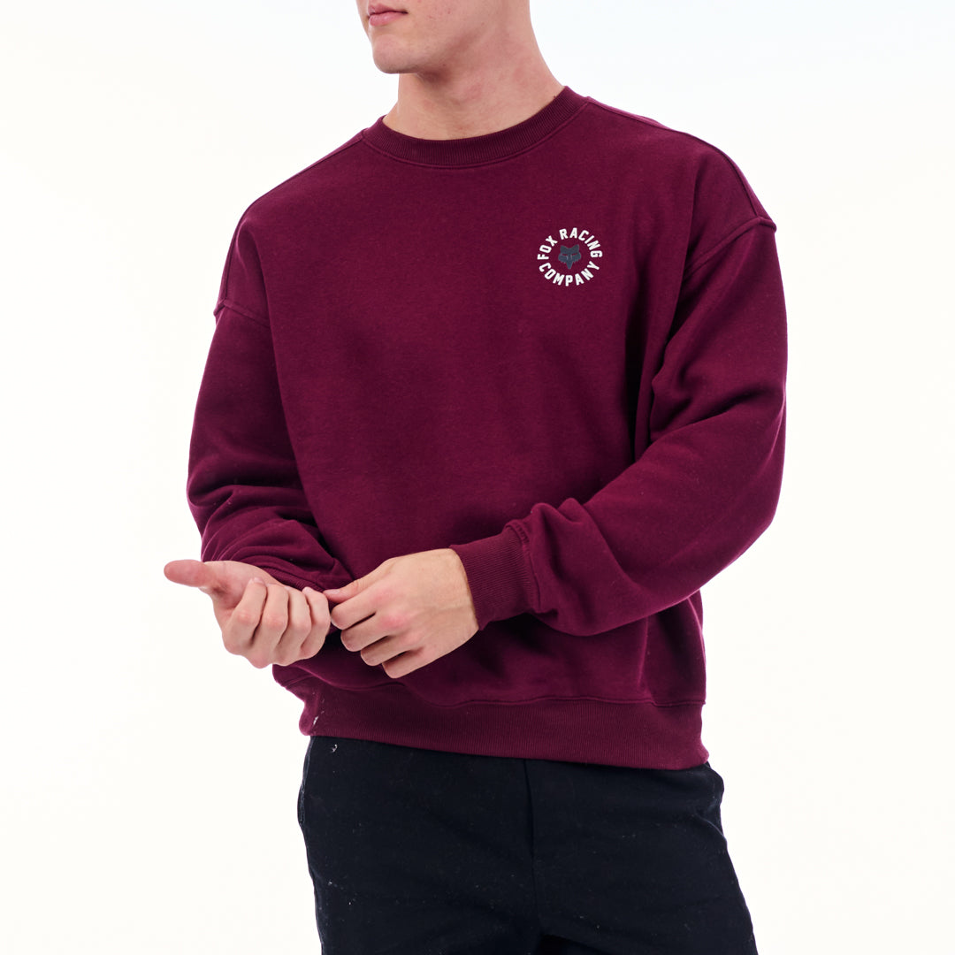 Person wearing a maroon sweatshirt with a logo on a white background