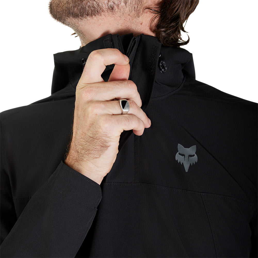 Person wearing a black jacket with a brand logo on a white background