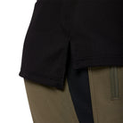 Close-up of a black sleeve and khaki pants with a visible brand logo.