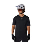 Person wearing a black t-shirt with a logo, white helmet, and sunglasses on a white background