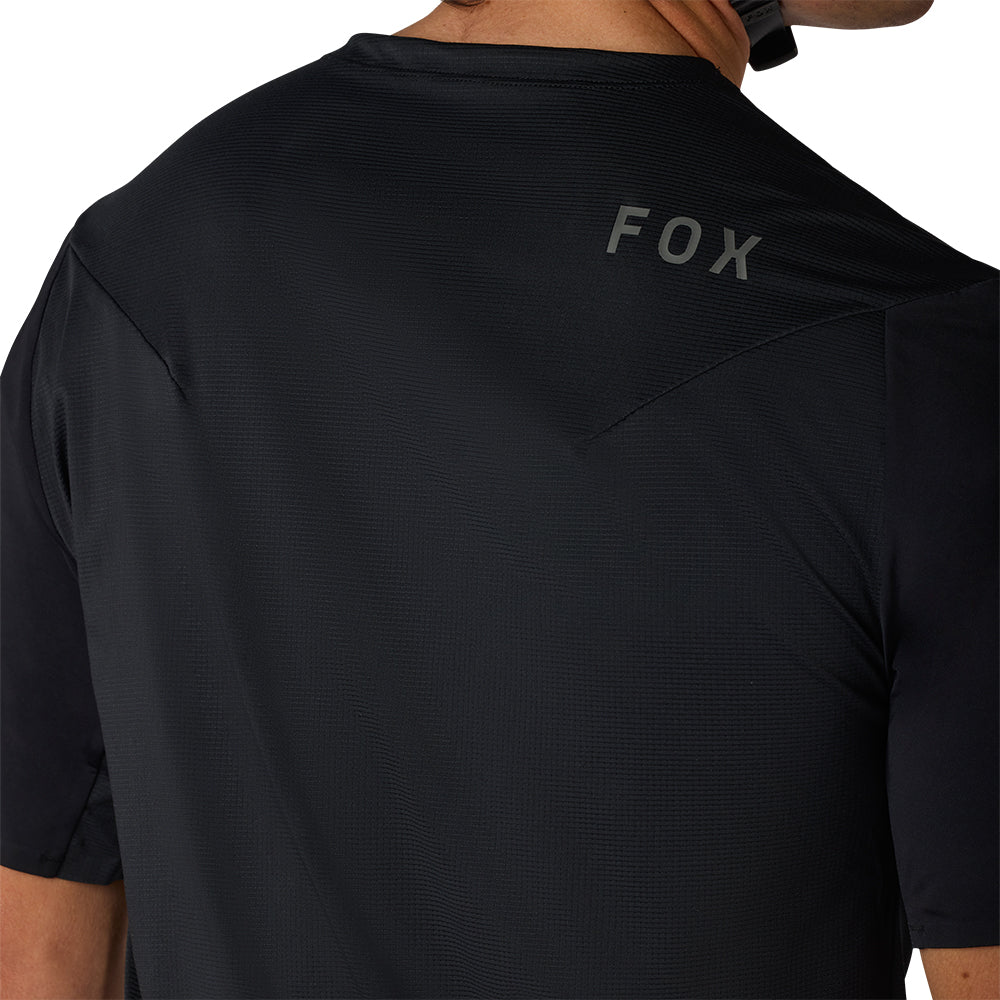 Black t-shirt with 'FOX' logo on the back, worn by a person.