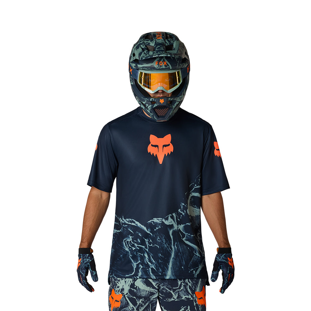 Person wearing a Fox Racing helmet, shirt, and gloves on a white background