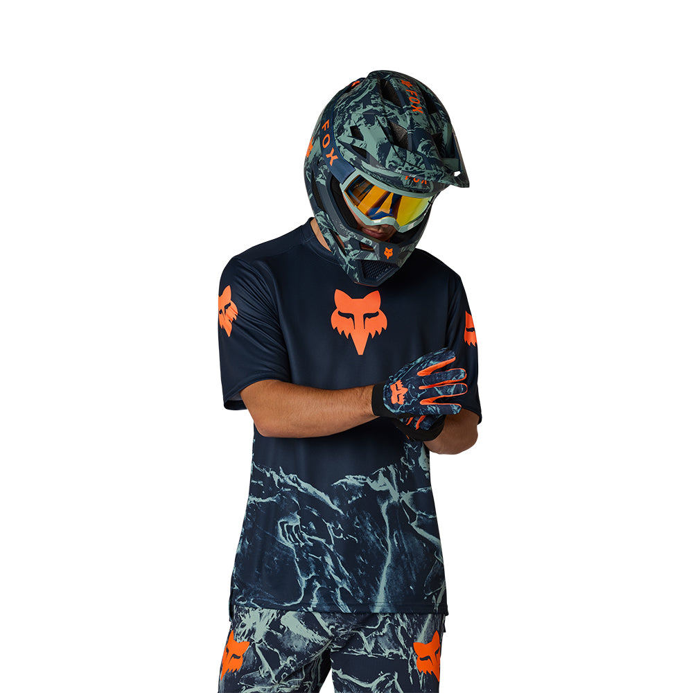 Person wearing a full motocross outfit with helmet, shirt, and pants on a white background