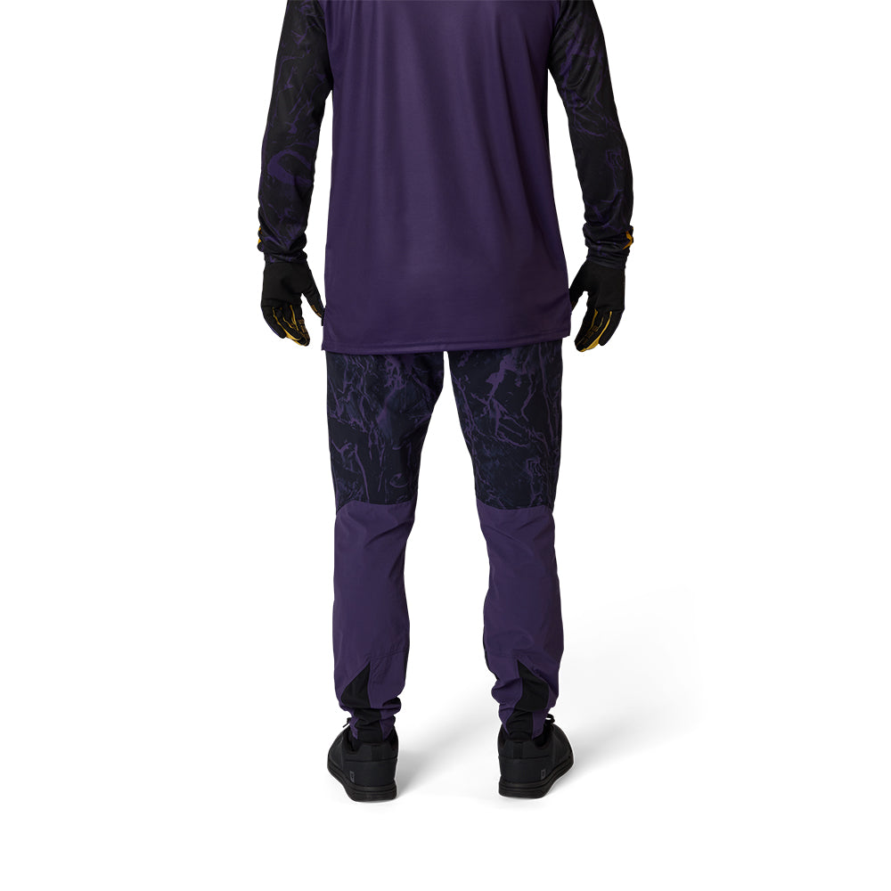 Person wearing a purple athletic outfit with black gloves and shoes on a white background