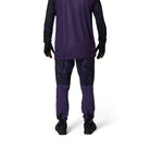 Person wearing a purple athletic outfit with black gloves and shoes on a white background