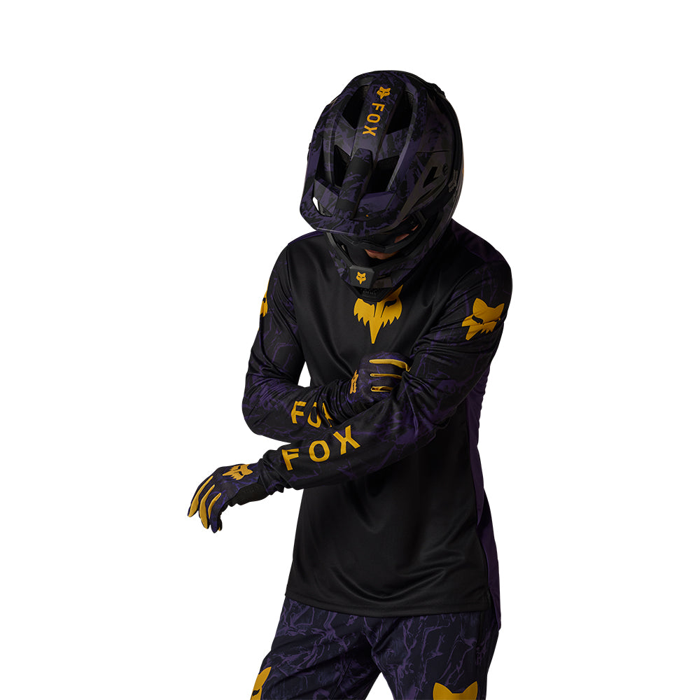 Person wearing a black and yellow motocross outfit with helmet on a white background