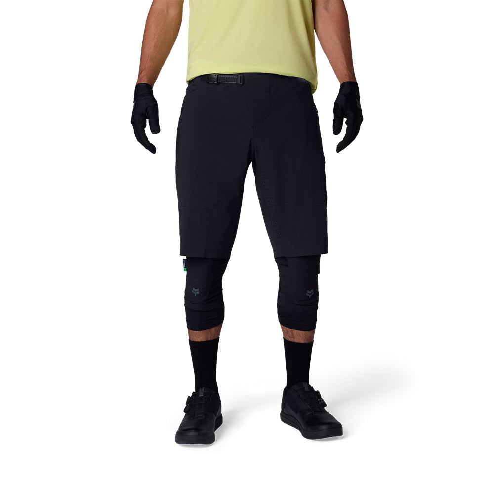 Person wearing black cycling shorts, gloves, and knee pads on a white background