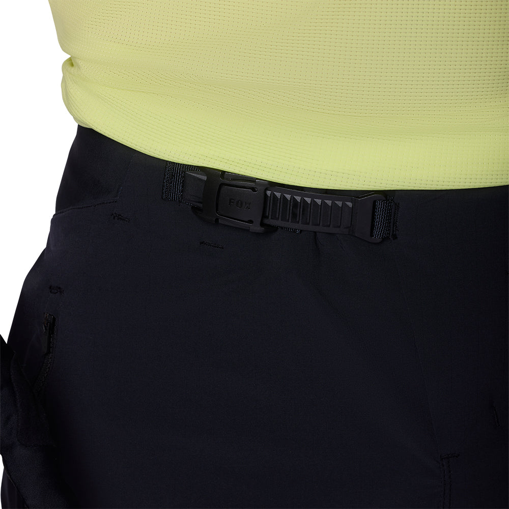 Close-up of black pants with a black belt and yellow top on a white background