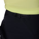 Close-up of black pants with a black belt and yellow top on a white background