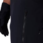 Close-up of a black jacket with a zipper and a gloved hand on a white background