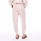 Person wearing a light pink outfit with matching pants on a white background