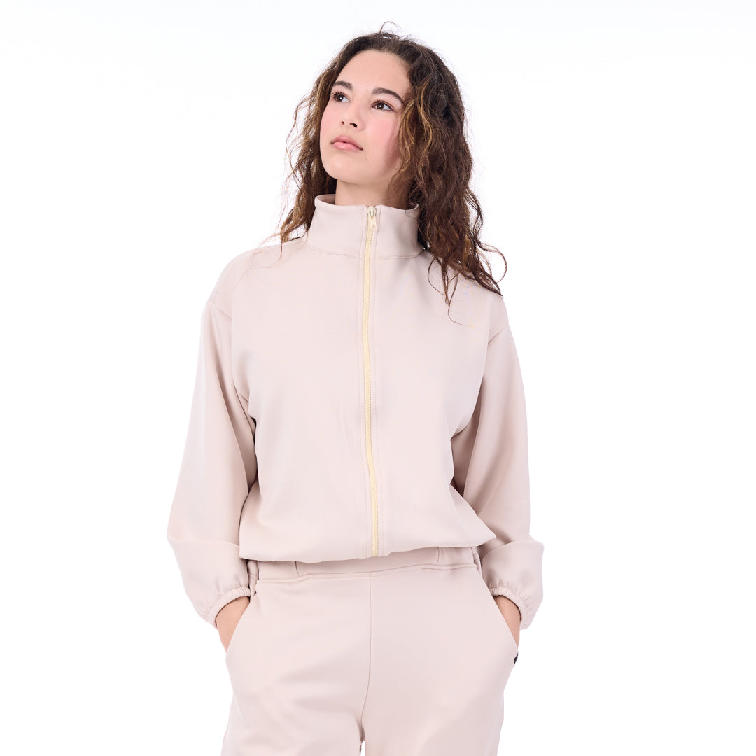 Woman wearing a beige tracksuit with a zipper on a white background