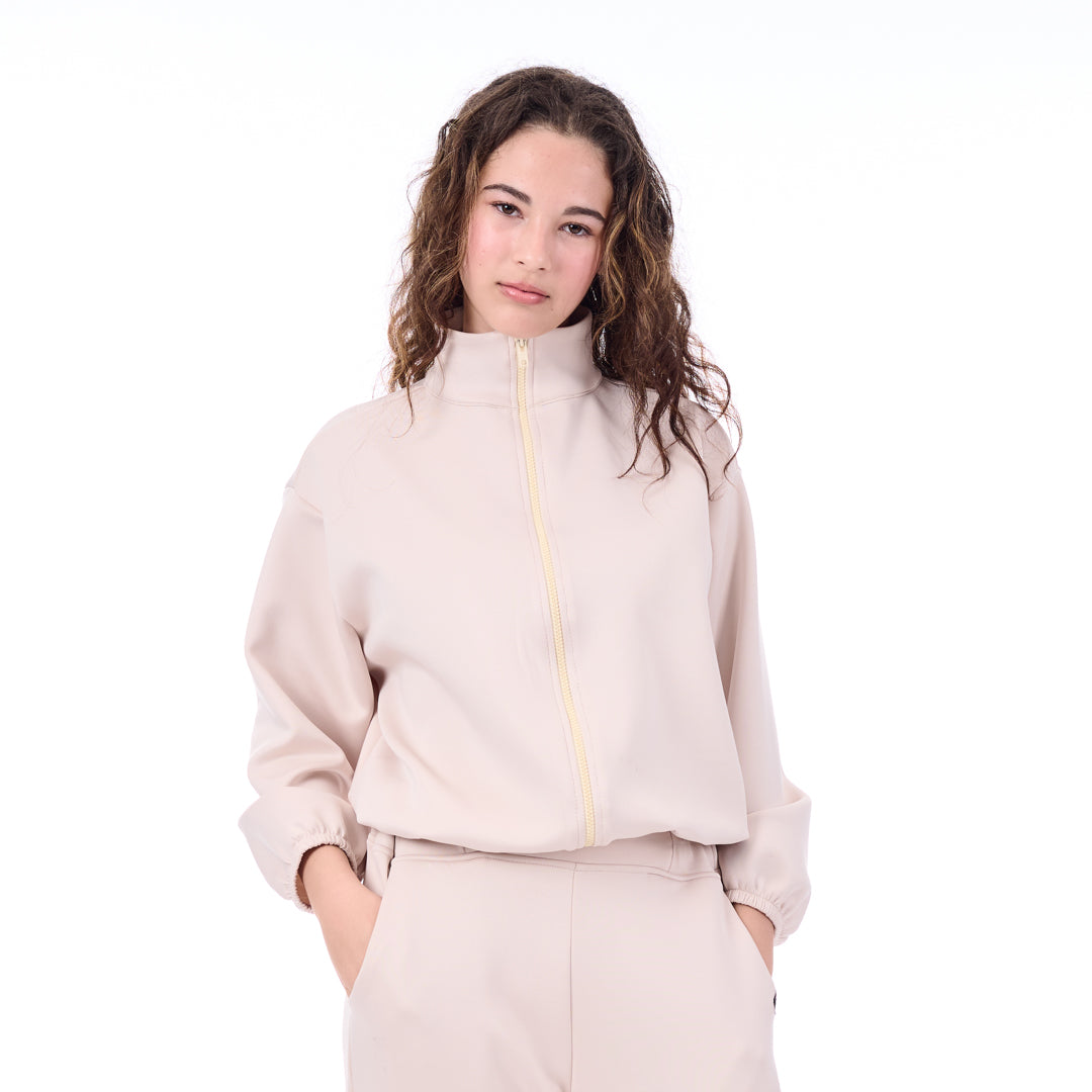 Woman wearing a light pink zip-up hoodie and pants on a white background
