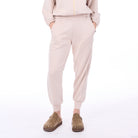 Person wearing beige jogger pants and brown shoes on a white background