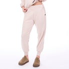 Person wearing light pink jogger pants and brown shoes on a white background