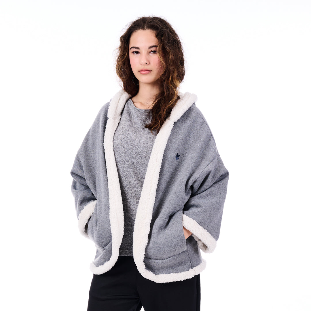 Woman wearing a gray poncho with white trim on a white background