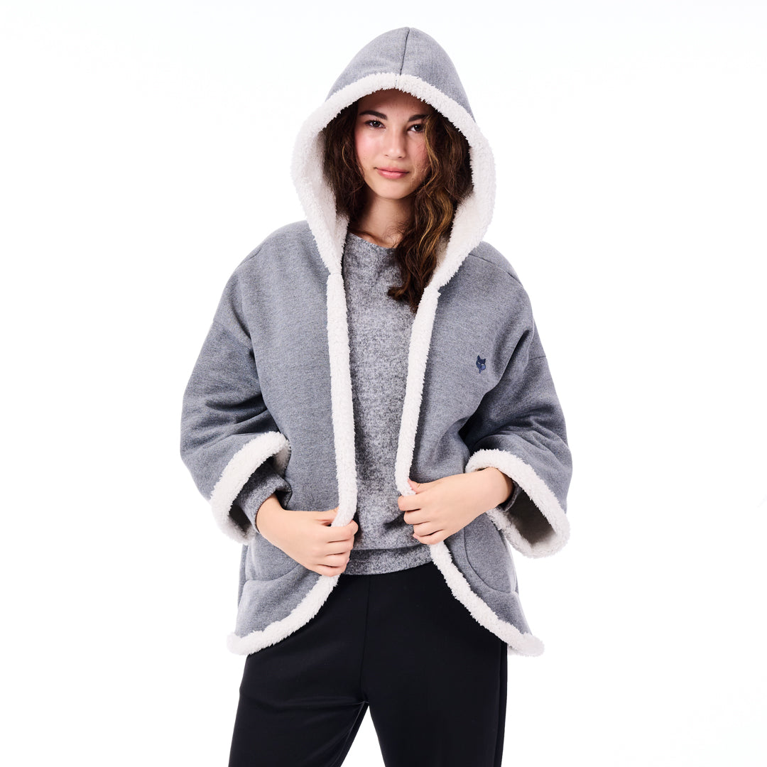 Woman wearing a gray hooded poncho with white trim on a white background