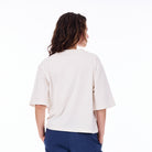 Person wearing a white oversized shirt and blue pants on a white background