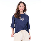 Woman wearing a navy blue t-shirt with a white graphic design on a white background