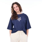 Person wearing a navy blue oversized shirt with a white floral design on a white background