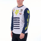 Person wearing a white and blue long-sleeve shirt with brand logos on a white background