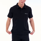 Person wearing a black polo shirt with a logo on a white background