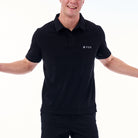 Person wearing a black polo shirt with a logo on a white background