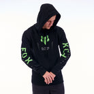 Person wearing a black hoodie with green text and logos on a white background