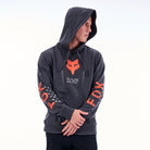 Person wearing a dark gray hoodie with orange Fox logo on a white background