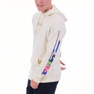 Person wearing a cream hoodie with colorful designs on sleeves against a white background