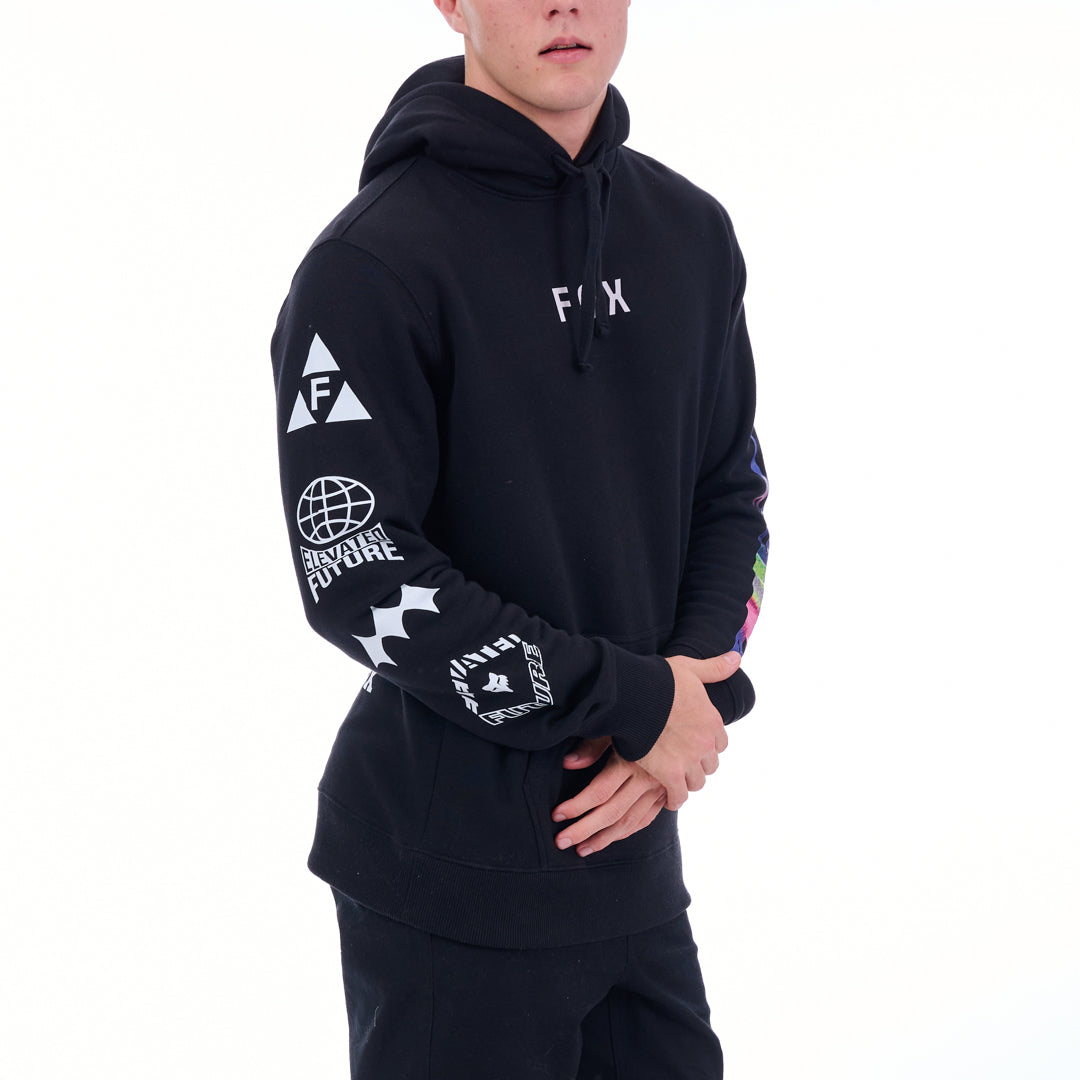 Person wearing a black hoodie with various logos on sleeves against a white background