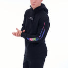 Person wearing a black hoodie with colorful designs on the sleeves against a white background